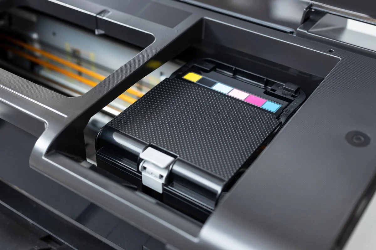Close-up of a printer carriage assembly with color-coded markings